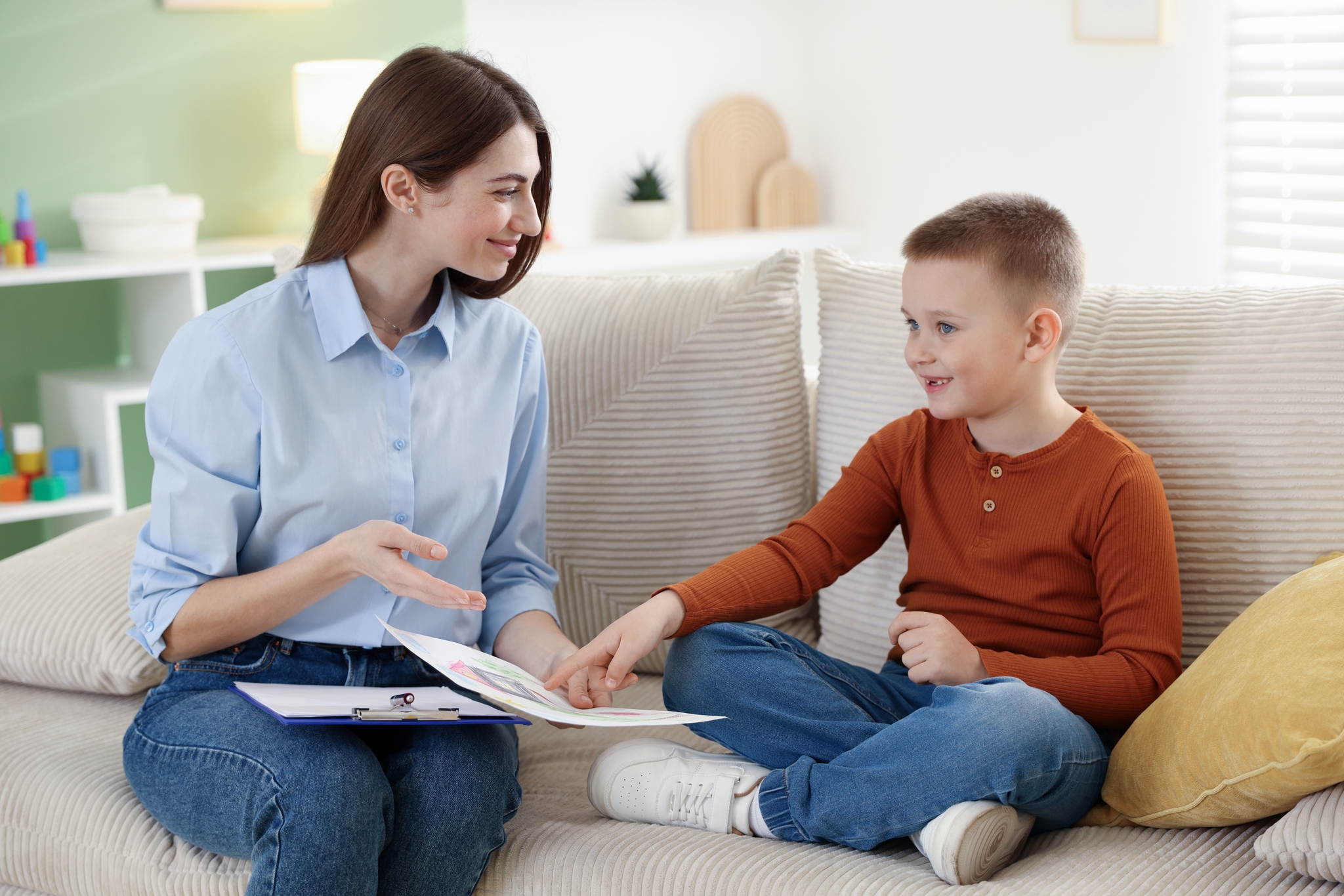 Psychologe arbeitet mit kleinen Jungen auf Sofa drinnen